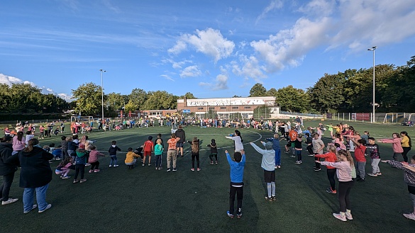 Alle Schülerinnen und Schüler wärmen sich gemeinsam für das Sportfest auf.